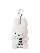 A small white plush bunny toy with a black and white striped scarf attached to it.