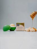 a jar of Manuka Honey & Macadamia Nut Butter, a box of the product, and a honey dipper.