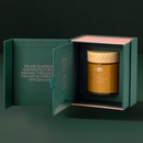 A jar of Manuka honey is displayed in a green box with a pink interior, set against a dark background.