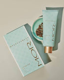 a mint-colored product packaging for a "Delicate's" product, along with a tube of the same product. The packaging has a light blue background and gold text, and the tube is placed next to it.