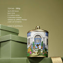 A decorative tin can with a house illustration and people, placed on a green surface.