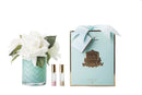 a bouquet of white roses in a glass vase, a box of Cote Noire perfume, and two small bottles of perfume.