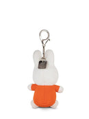 A small stuffed bunny toy with an orange shirt and a metal tag attached to it.