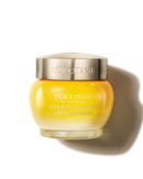 A jar of L'Occitane Immortelle Creme Jeunesse, a yellow cream product, is shown against a black background.