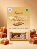 a product called "My Lips Are Sealed" by Lucamar, a natural and organic lip balm. The product is displayed on a table with a small box of the lip balm and several pieces of the product, likely a type of candy or confection.