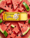 a tin of Lucamar lip balm surrounded by slices of watermelon and black seeds.