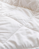 A close-up view of a white, fluffy, and wrinkled fabric, possibly a blanket or comforter.