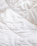 a close-up view of a white, crumpled fabric, possibly a blanket or quilt.