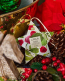 A star-shaped ornament with a label that reads "CIRCA RASPBERRY & RHUBSINI SINCE 1853" is surrounded by various holiday decorations, including pine cones, berries, and a green ornament.