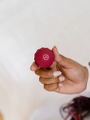 A hand holding a small, red object with a logo on it.