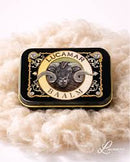 A black tin can with a gold and black label featuring a picture of a ram's head and the text "LUCAMAR BAALM".