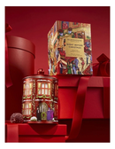 a red tin can with a Christmas-themed design, placed on top of a red gift box, with a red ribbon and other red objects in the background.