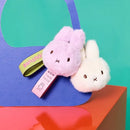 two plush bunny keychains, one pink and one white, sitting on a blue surface.