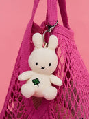 A white stuffed bunny toy is hanging from a pink mesh bag.