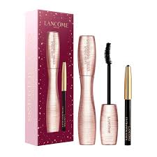 a set of makeup products from the Lancome brand, including a mascara, eyeliner, and an eyelash curler.