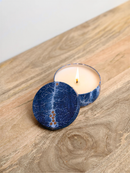A blue and white ceramic candle holder with a lit candle sits on a wooden surface.