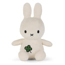 A white stuffed bunny toy with a green clover design on its chest.