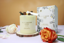a candle and a box of candles, both with floral designs, placed on a table with flowers.