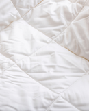 a close-up view of a white, crumpled fabric, possibly a blanket or quilt.