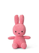A pink, corduroy stuffed bunny toy is sitting upright on a white background.