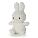 A white stuffed bunny toy with black eyes and a black nose is sitting on a white surface.