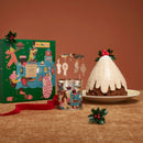 a festive holiday scene with a Christmas-themed box, a decorated Christmas tree, a cake, and a tin can.