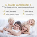 a happy family of four - a man, a woman, and two children - lying on a bed and smiling.