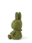 A green stuffed bunny toy is sitting on its back with its arms and legs spread out.
