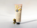 A tube of coconut and finger lime hand cream with a decorative label, placed on a white surface with a few pieces of the cream visible.