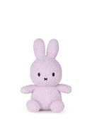 A small, pink stuffed bunny toy is sitting on a white background.