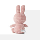 A pink stuffed bunny toy is sitting on a white surface.
