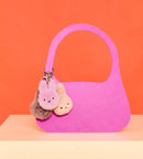 A pink handbag with three small, plush bunny keychains attached to it.