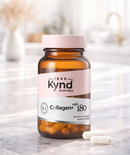 A bottle of Kynd Collagen 180 capsules is placed on a marble countertop, with a blurred background.