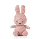 A pink, striped stuffed bunny toy is sitting on a white surface.