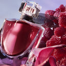 A close-up image of a perfume bottle with a red liquid inside, surrounded by fresh raspberries.