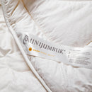 a close-up view of a white fabric, possibly a blanket or quilt, with a label attached to it. The label appears to be a description or information about the fabric, likely providing details about the material, care instructions, or other relevant information.