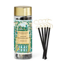A tall glass jar with a gold lid, filled with black sticks, and a label that reads "GLASSHOUSE FLAMMAINE WINTER WONDERLAND FROZEN FIR & SNOW GUM".