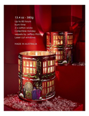 a red candle holder with a winter scene design, placed on a red surface with snow around it.