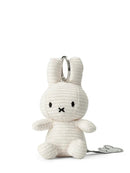 A white stuffed rabbit toy with black eyes and a black mouth is sitting on a white surface.