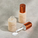 two bottles of Syrene Black Pearl Illuminating Serum, with one bottle open and the other one closed, both containing a white substance.