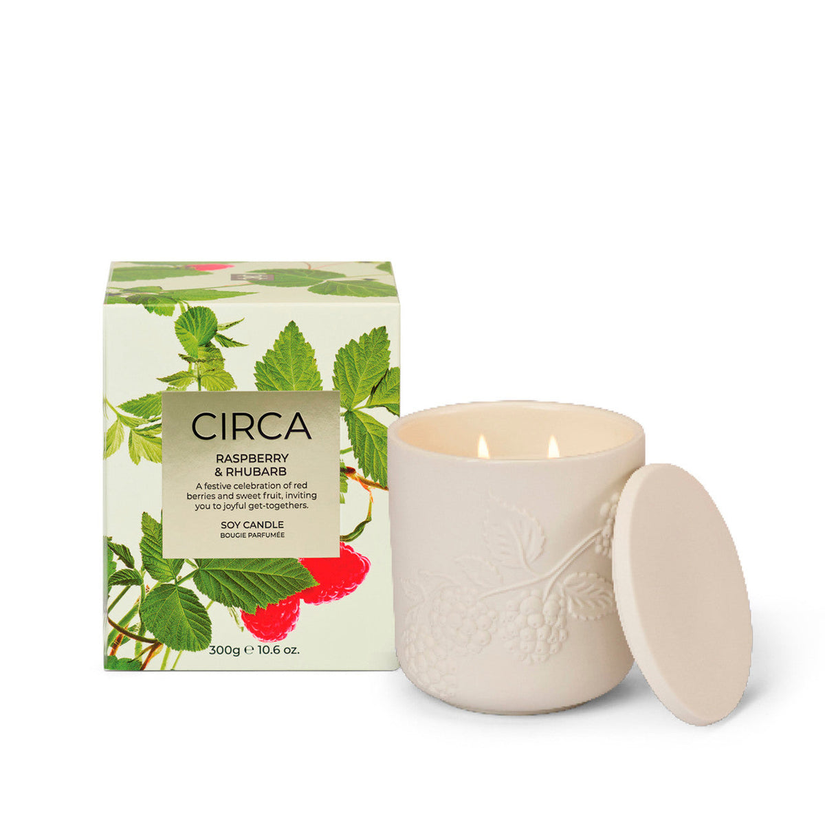 a white ceramic candle with a lid and a box with a raspberry and rhubarb design, both placed on a white background.