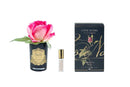 a pink rose in a black vase, a small bottle of perfume, and a black box with gold lettering.