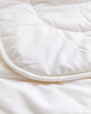 A close-up view of a white, fluffy, and soft-looking fabric, possibly a blanket or quilt.