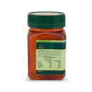 a bottle of honey with a green cap and a label that provides information about the product.