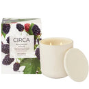 a white soy candle and a box of blackberries and plum.