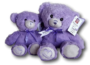 Two purple teddy bears with purple bows sit together against a black background.
