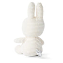 A white stuffed bunny toy is sitting on a white surface.