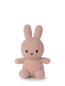 A pink, furry stuffed bunny toy is sitting on a white background.
