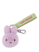 A keychain with a purple bunny head and a green strap with the text "FLUFF COUTURE" printed on it.