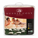 a family of three, a man, a woman, and a child, sitting together on a bed with sheep in the background. The packaging for the AussieCody Pure Wool Quilt is visible, and the text on the packaging indicates that it is a single bed size.